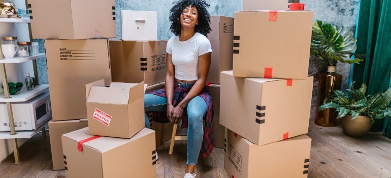 woman sitting on packing boxes presenting how to get ready for moving to Live Oak